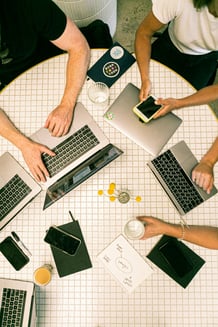 team of researchers doing work at a table with their laptops