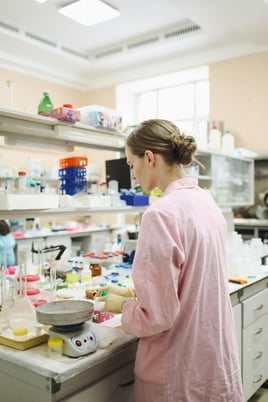 scientist expert researcher freelance researcher in a pink lab coat standing at a lab table doing science research