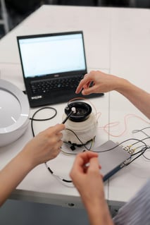 new product development: two people attaching wires to a product with a computer in the background